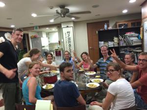 un grupo de personas sentadas alrededor de una mesa comiendo comida en Hwaseong Guesthouse en Suwon