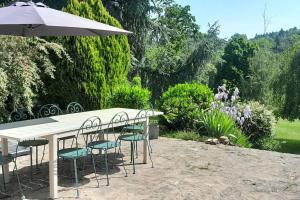 a white table with chairs and an umbrella at Villa au calme avec grande piscine in Villerest