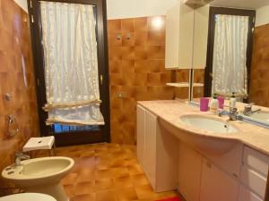 a bathroom with a sink and a toilet and a mirror at Villa The Central Tree - Lake View and Terrace in Sala Comacina