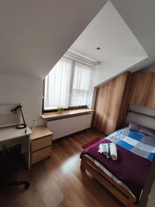 a bedroom with a bed and a desk and windows at Kora in Sosnowiec