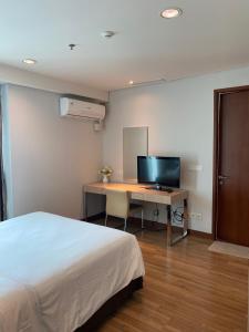 1 dormitorio con 1 cama y escritorio con TV en The H Tower Residence by YLS Stay en Yakarta