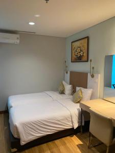 a bedroom with two beds and a table and a desk at The H Tower Residence by YLS Stay in Jakarta