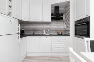 a white kitchen with a sink and a refrigerator at Cozy Apartment Gdańsk Morena Rakoczego by Rent like home in Gdańsk