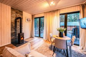 een woonkamer met een tafel en een houtkachel bij Heban Forest Cabin&SAUNA Starlink in Tomczyn