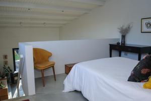 ein Schlafzimmer mit einem weißen Bett und einem Stuhl in der Unterkunft Oranje Meul in Paarl