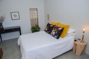 ein Schlafzimmer mit einem weißen Bett und gelben Kissen in der Unterkunft Oranje Meul in Paarl