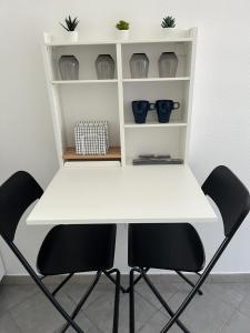 une table blanche et deux chaises dans une pièce dans l'établissement Le Studio M aux portes de Lille, à Marquette-lès-Lille