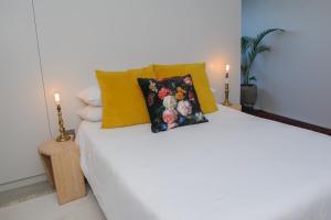 ein weißes Bett mit gelben Kissen und zwei Kerzen in der Unterkunft Oranje Meul in Paarl