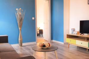 un salon avec une table et un mur bleu dans l'établissement Cocon Rue Ecuyère - Calme- 2ch - 6pers, à Caen