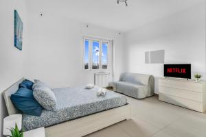 een witte slaapkamer met een bed en een stoel bij ROG27-Large apartment with transport close to home- in Milaan