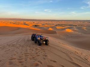Adrouineにあるmerzouga berber tentsの砂漠を走る一団のオートバイ