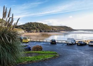 a parking lot with cars parked next to a beach at Beach haven retreat, Caswell Bay in Swansea