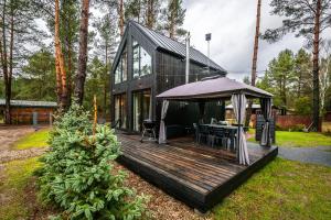 a black house with a wooden deck with a table at Heban Forest Cabin&SAUNA Starlink in Tomczyn