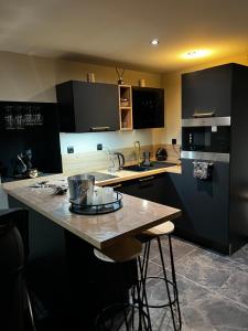 a kitchen with black cabinets and a wooden counter top at Douceur du Charme - Love-room à Charmes entre Epinal et nancy in Charmes