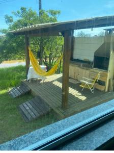 a porch with a hammock and two chairs on it at Pousada dos Reis in Barra de Ibiraquera