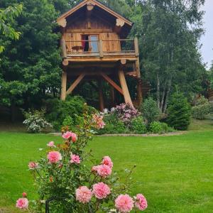 una casa del árbol en un patio con flores rosas en La quiete di Ileana Sofian en Pamparato