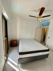 a bed in a room with a ceiling fan at APTO DE FRENTE PARA O MAR - CARAGUATATUBA. in Caraguatatuba