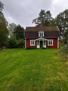 LinnerydにあるBastanäs Rosenbergの前に緑の芝生がある赤い家