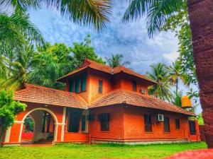 uma casa laranja com um telhado com palmeiras em Ambara Kovilakam Private Pool Villa by Travent Mug em Rāmanagaram