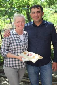 Un uomo e una donna che tengono in mano un piatto di cibo di Chateau Ateni Cottages a Gori