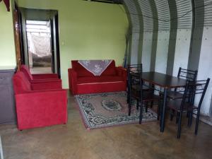 Habitación con mesa, sofá rojo y silla en Casita Doña Isabel, en Bijagua