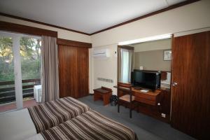 um quarto de hotel com uma cama e uma televisão de ecrã plano em Hotel Senhora do Castelo em Mangualde