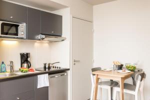 cocina con mesa pequeña y microondas en Aparthotel Adagio Access Paris Massy Gare, en Massy