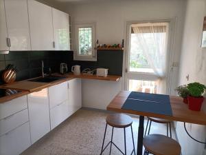 a kitchen with white cabinets and bar stools in it at Grande maison 3 chambres - Jardin, terrasse et parking - Bord de mer in Torreilles