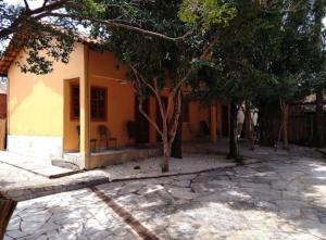 a small yellow house with trees in front of it at Recanto Rocas in Pirenópolis