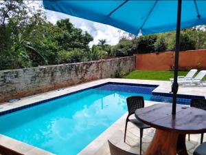 a swimming pool with a table and an umbrella at Recanto Rocas in Pirenópolis