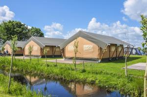 a tent in a field next to a river at Camping De Boerinn in Kamerik