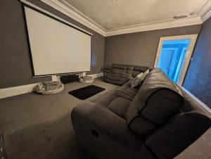 a living room with a large couch and a large screen at Bonnyside House in Bonnybridge
