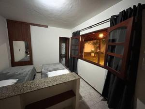 um pequeno quarto com 2 camas e uma janela em Suíte c/ar e varanda perto do Parque de Exposições em Patos de Minas