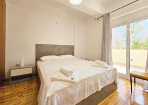 a white bedroom with a bed with towels on it at "Athena 2" appartment" near Athens airport !!! in Kouvarás