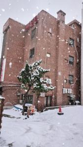 a large brick building with a tree in the snow at Mokhwajang Motel in Goyang