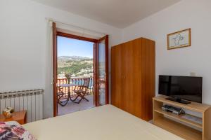 1 dormitorio con cama, TV y balcón en Villa Valjalo, en Dubrovnik