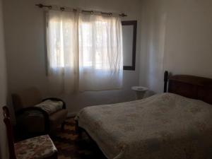 um quarto com uma cama, uma janela e uma cadeira em La casa de la abuela em Rivera