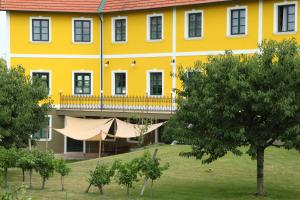 um grande edifício amarelo com varanda e árvores em Oldtimer Motorhotel Guntramsdorf em Guntramsdorf