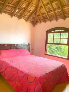 a bedroom with a red bed with a window at Casa del Artista, Ilha Grande Araçatiba in Praia de Araçatiba