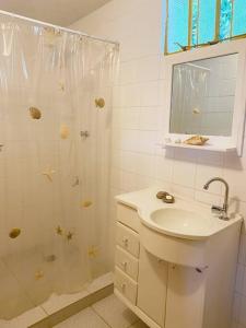 a white bathroom with a shower and a sink at Casa del Artista, Ilha Grande Araçatiba in Praia de Araçatiba