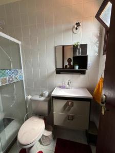 a bathroom with a toilet and a sink and a mirror at Casa em Praia Seca, Araruama. in Araruama
