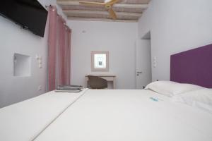 a bedroom with a large white bed and a tv at Flaskos Village Fanari in Mýkonos City