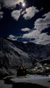 Una vista nocturna de un granero con la luna en el cielo en view, en Kazbegi