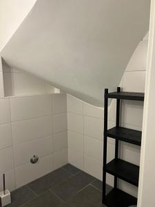 ducha en el ático con azulejos blancos y estante negro en Pension Imhof, en Oyten