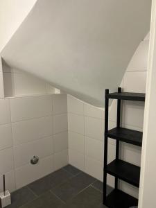 a attic shower with white tile and a black shelf at Pension Imhof in Oyten +22 photos