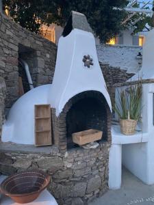 a stone pizza oven with a table and a plant at Flaskos Village Fanari in Mýkonos City