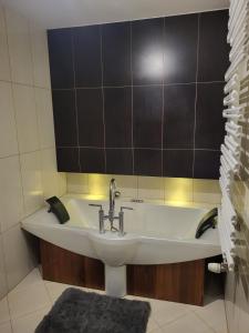a bathroom with a sink and a black tiled wall at Lemuria Przytulny pokój Chojnowska in Legnica