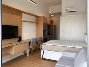 een slaapkamer met een bed en een bureau met een televisie bij Apt. inteiro recém-reformado - Vila Mariana in Sao Paulo