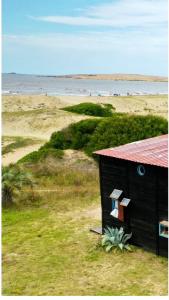 uma pequena casa preta com uma janela numa praia em Satori em Barra de Valizas