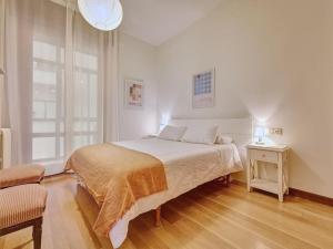 a white bedroom with a bed and a table at Apartamento El Cuarto Rey by Clabao in Pamplona